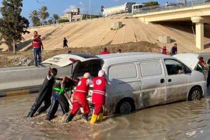 Libyan Red Crescent members work on opening roads engulfed in floods.
